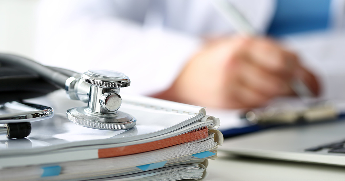 A doctor reviews practice resources for continuing education, with a stethoscope and paperwork in the foreground.