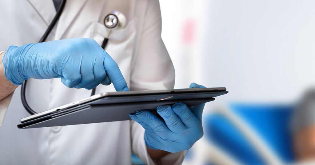 A doctor's gloved hands use a tablet to access a medical release form.